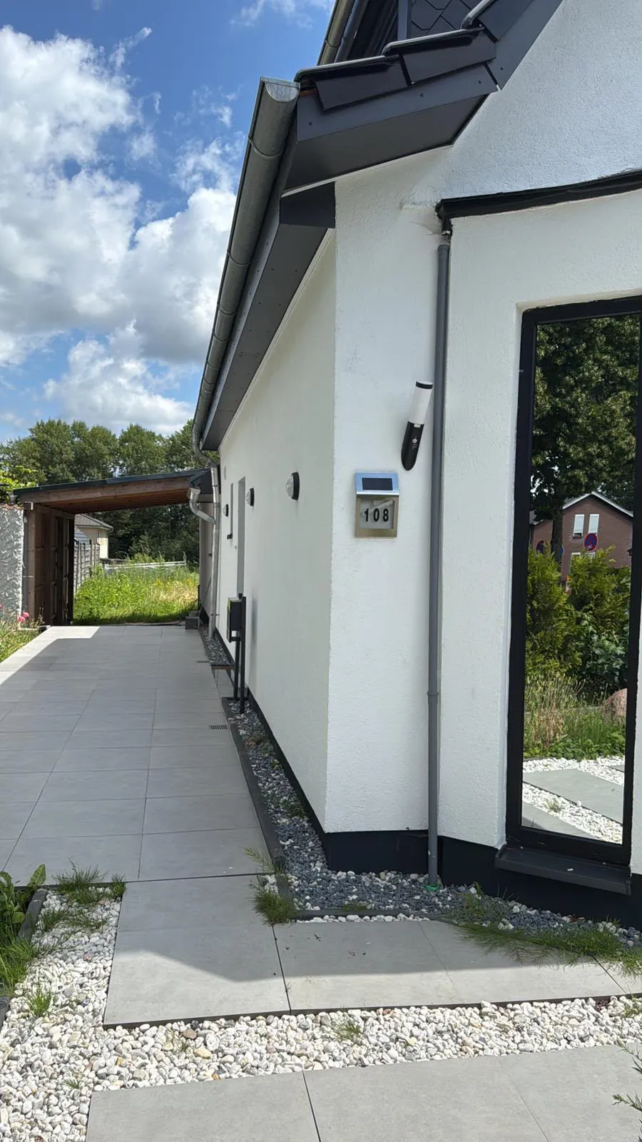 Gepflasterter Hauszuweg mit großformatigen Platten und Kiesbett