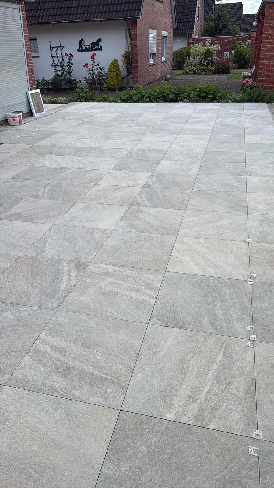 Neu verlegte Terrassenfläche aus grauen Großformatplatten mit Fugenkreuzen